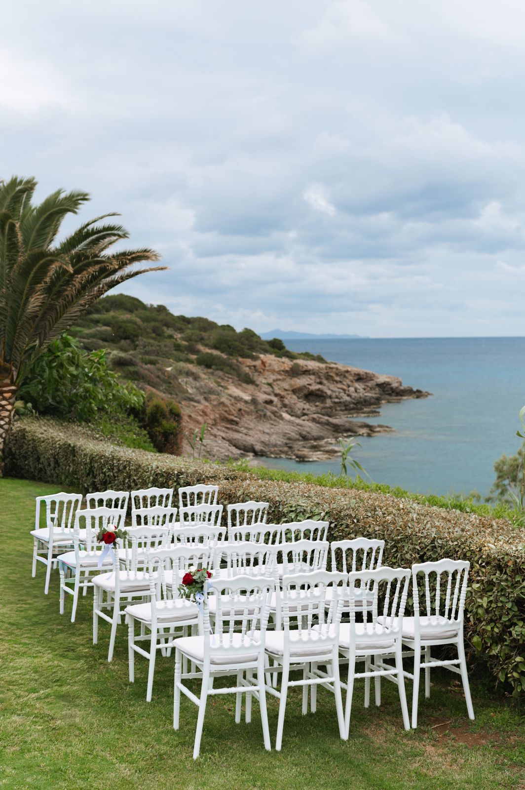 Rows of white chairs on a lawn above the rocky coast at Ktima 48, Athens Riviera