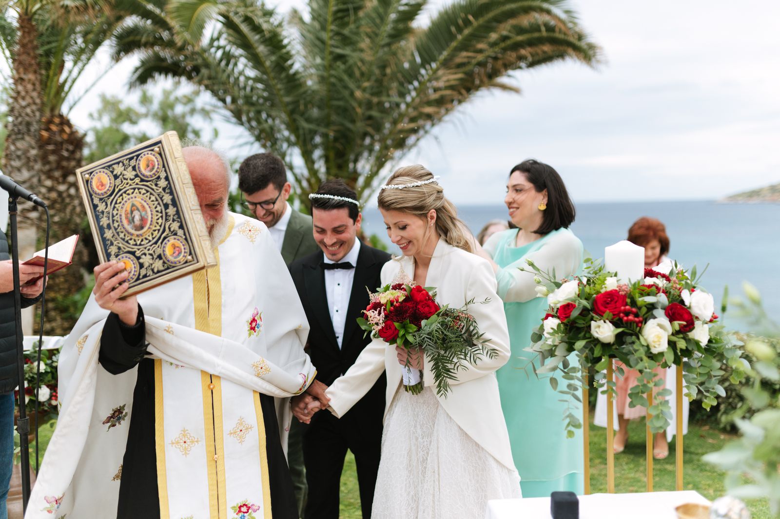 Greek Orthodox priest with the gospel book leading the crowned couple at Ktima 48, Anavyssos
