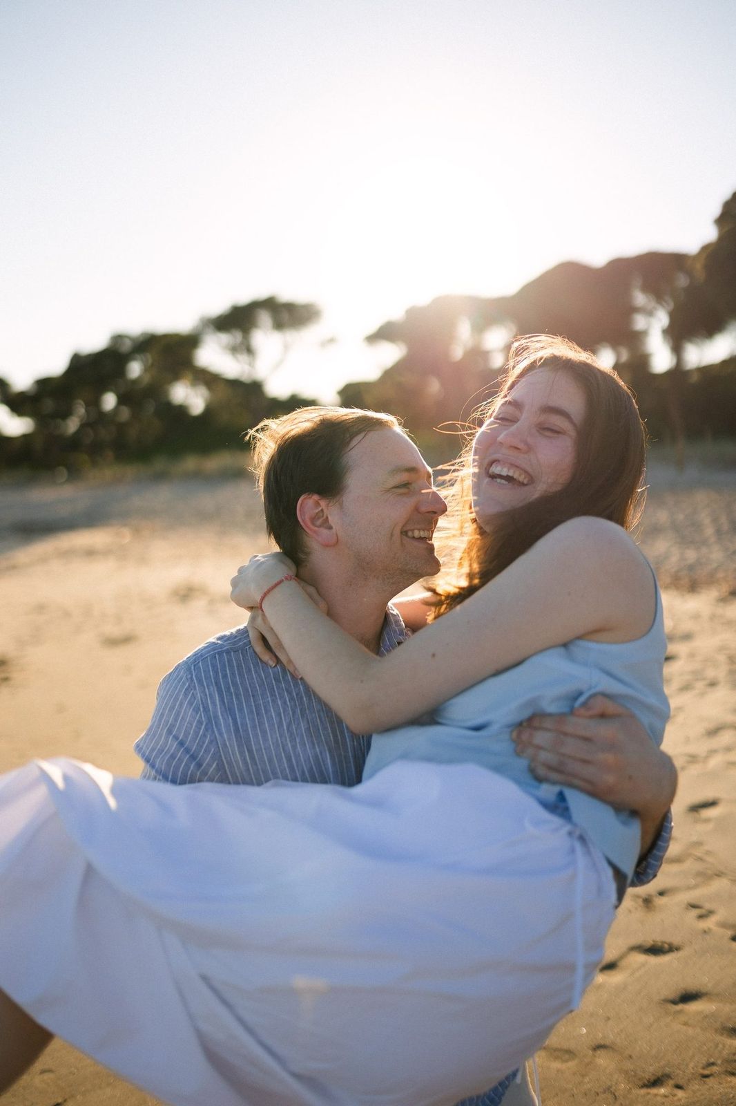 A couple laughing on a Greek beach at golden hour in summer
